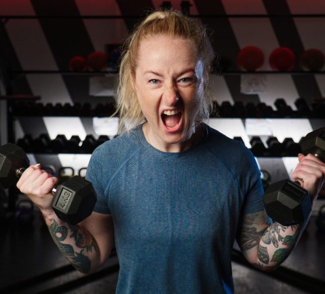 Gym – Person som lyfter hantlar under ett inspirerande träningspass på USM Utopia i Umeå.