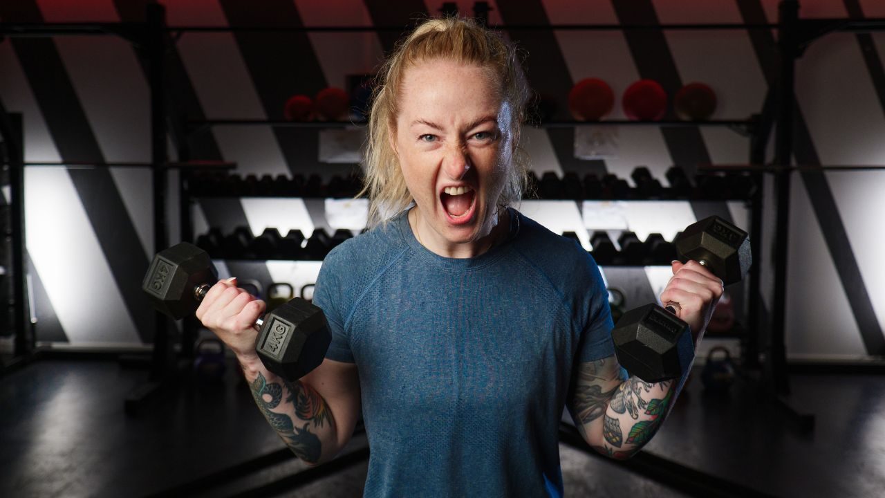 Gym – Person som lyfter hantlar under ett inspirerande träningspass på USM Utopia i Umeå.