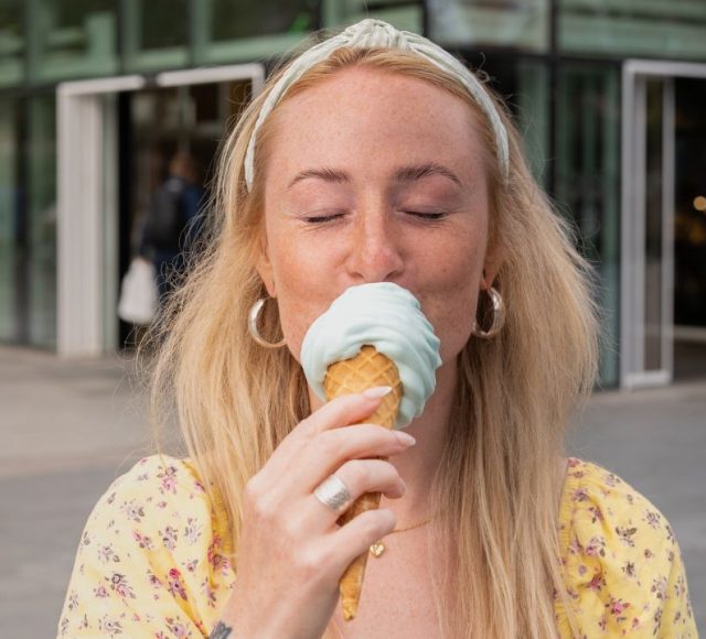 Tjej njuter av en svalkande glass utanför kvarteret Utopia.