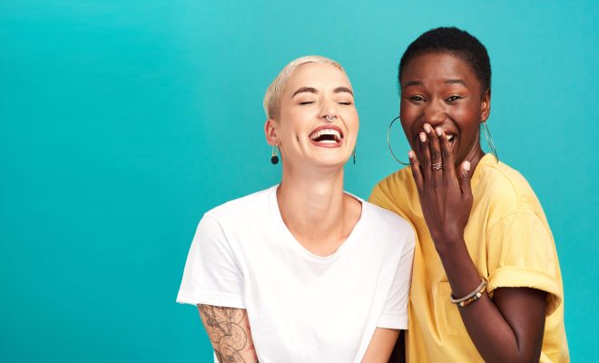 Studio shot of two happy young women posing together against a turquoise background