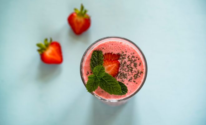 Naked Juicebar - smoothie i glas med jordgubbar liggande bredvid.